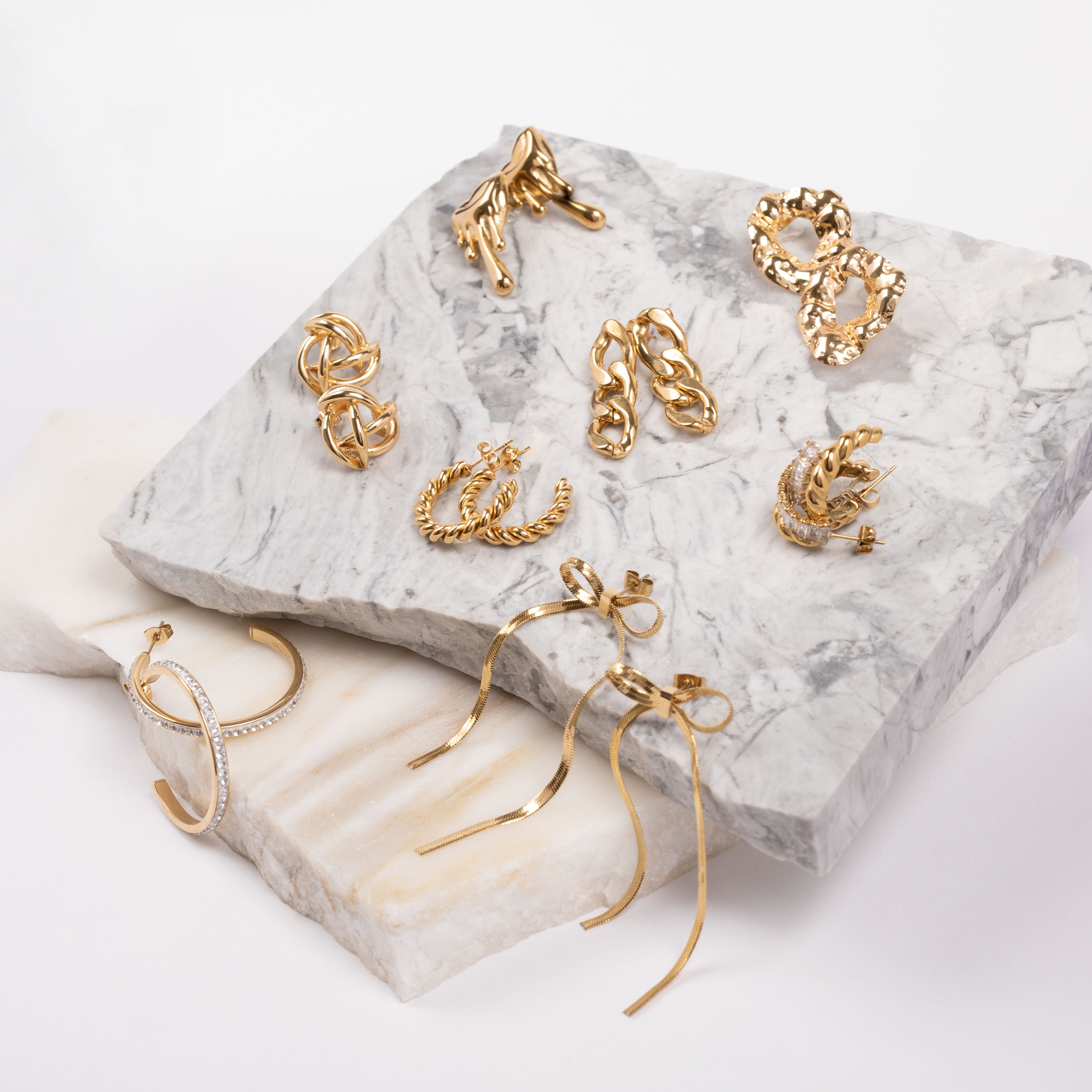 Gold fashion earrings displayed on a marble surface