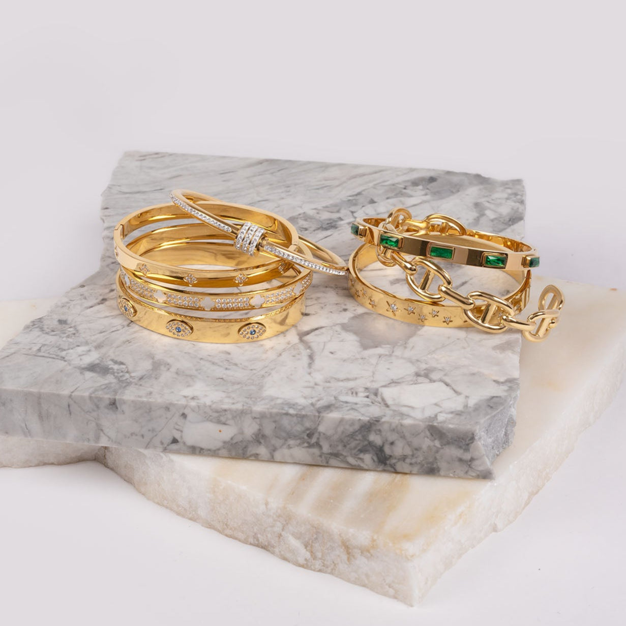 Gold bracelets and bangles on a marble stand with a white background